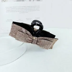 Detail of elegant bow hair claw clip with sparkling rhinestones on minimalist background