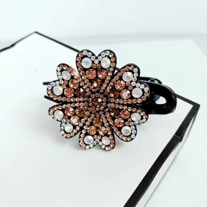 Macro detail of elegant floral hair claw clip with champagne and iridescent rhinestones