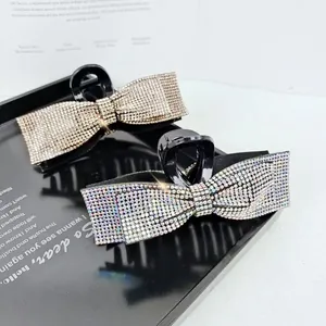 Detail of elegant bow hair claws featuring sparkling rhinestones in champagne and white