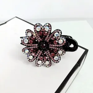 Macro view of large flower hair claw clip with pink rhinestones on black acrylic base