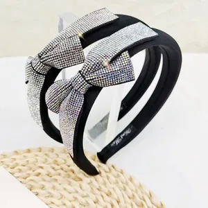 Detailed view of black sponge headband with glittering rhinestones and oversized bow