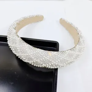 Détail macro de perles blanches et strass sur un serre-tête large et épais de luxe