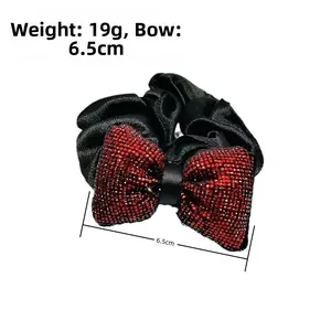 Détail d'un chouchou à nœud en satin noir avec strass rouges et dimensions de 6,5 cm