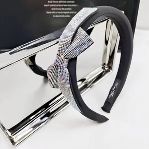 Elegant black fabric headband with sparkling crystal bow on silver metal display stand
