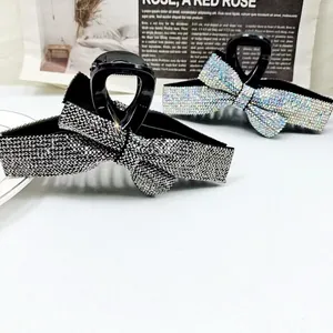 Vue détaillée de pinces à cheveux à nœud en strass brillants sur une table blanche