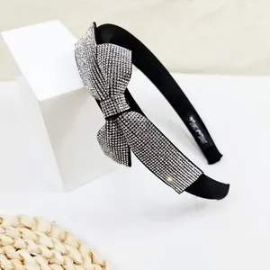 Detail of elegant black wide headband with sparkling rhinestone bow on white platform