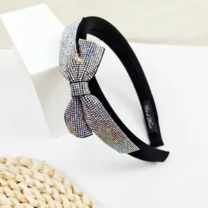 Close-up of luxury sponge headband featuring sparkling rhinestone bow on wide black base