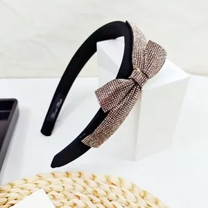 Detailed view of handmade black fabric headband featuring a sparkling rhinestone bow