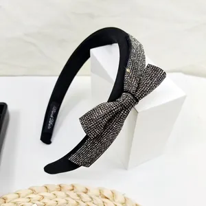 Detail of elegant black sponge headband featuring a large bow with silver rhinestones