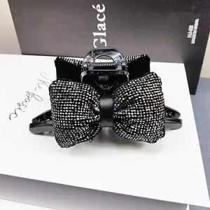 Gros plan d'une pince à cheveux nœud noir avec strass brillants sur une boîte blanche