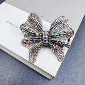 Detailed close-up of a bow hair clip featuring dense rainbow AB rhinestones on a dark base