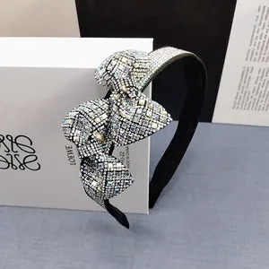 Detailed close-up of a wide sparkling crystal bow headband resting on a gift box