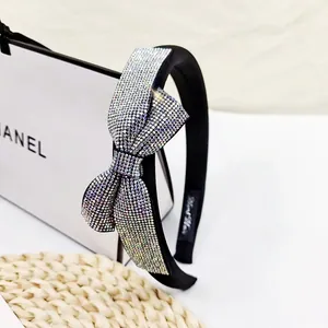 Macro shot of luxury black fabric headband with sparkling crystal bow on woven mat