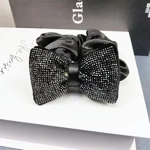 Vue macro d'une pince à cheveux en velours noir ornée d'un nœud en strass brillants