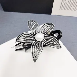 Dettaglio della pinza per capelli nera con strass argentati e una perla centrale fine