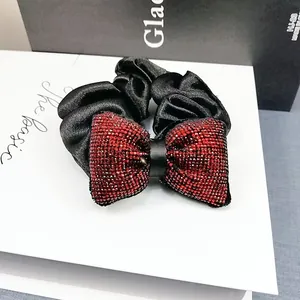Gros plan d'une pince à cheveux en satin avec strass rouges sur un coffret cadeau