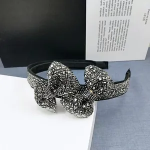 Macro detail of bow headband featuring sparkling silver rhinestones on black fabric base