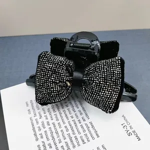 Gros plan des strass brillants sur la pince à cheveux nœud noir doublée de velours