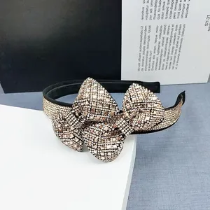 Detailed view of luxury bow headband with shimmering champagne crystals on black fabric base