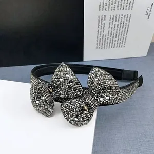 Macro view of crystal encrusted black bow headband with sparkling silver rhinestones