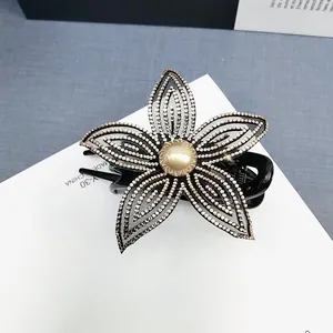 Dettaglio dell'elegante molletta a fiore nero con strass e perla centrale
