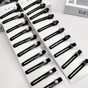 Lot de barrettes en velours noir avec lettres en perles et nœuds en cristal sur carte