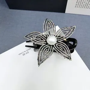 Dettaglio della pinza per capelli a fiore nero con strass luccicanti e perla centrale