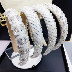 Detailed view of four luxury white crystal headbands displayed on golden stand