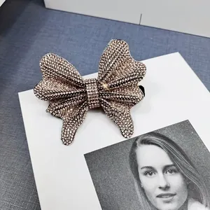 Detailed close-up of sparkling full rhinestone bow hair clip on a minimalist background