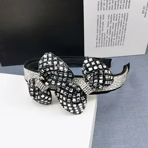 Detailed view of wide black headband with crystal encrusted bow and sparkling rhinestones