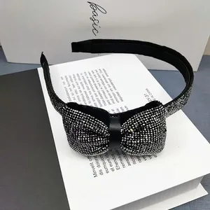 Détail du serre-tête nœud noir élégant avec strass argentés sur décor minimaliste