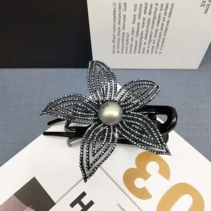 Dettaglio della pinza per capelli a fiore in rete con strass scuri e perla centrale