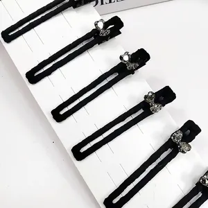 Détail de six barrettes à cheveux en tissu noir ornées de strass étincelants en cœur