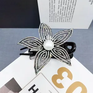 Dettaglio di elegante fermaglio a fiore in rete con strass lucidi e perla centrale