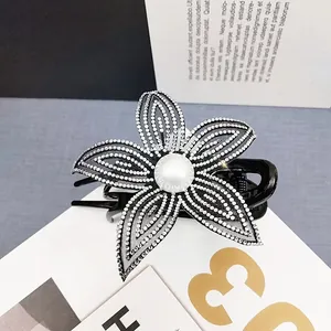 Dettaglio macro della molletta per capelli a fiore con strass e perla bianca lucida