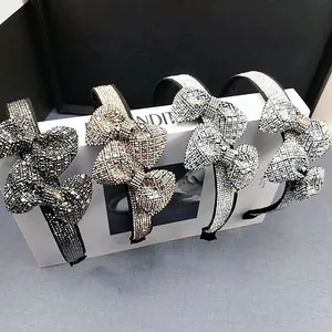 Detail of four crystal bow headbands in black, gold, silver and white on a display box