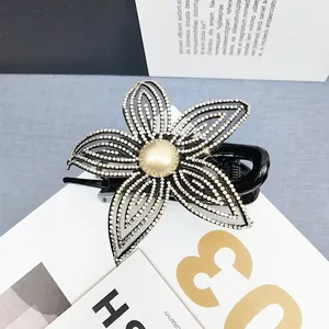 Dettaglio di elegante pinza per capelli a fiore in rete nera con strass e perla centrale
