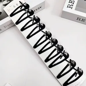 Détail de dix barrettes noires en forme de V avec cristaux et nœuds sur leur support