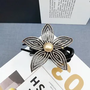Dettaglio della molletta a fiori con strass argento e perla sintetica centrale