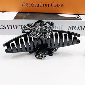 Détail d'une grande pince à cheveux noire de 13cm avec un nœud étincelant en strass