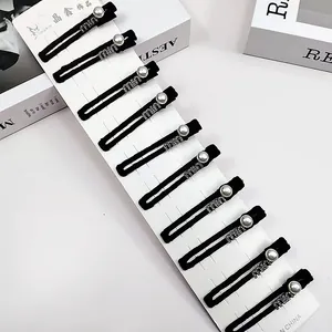 Vue détaillée de 10 barrettes noires ornées de perles et de strass brillants sur carte