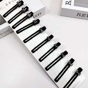 Lot de 10 barrettes en velours noir avec nœuds en strass argentés sur carte support