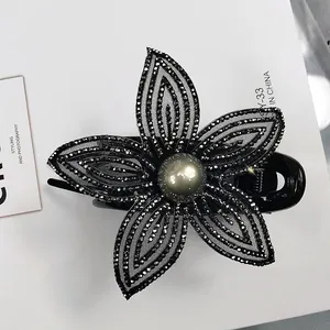 Dettaglio del fermaglio per capelli a fiore in rete nera con strass e perla grigia