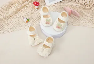 Dettaglio di scarpe da principessa per neonata con fiocco in pizzo e decoro di ciliegie