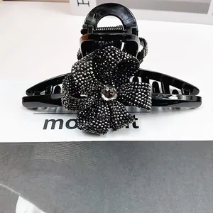 Détail macro d'une grande pince à cheveux noire avec nœud en strass et pierre facettée