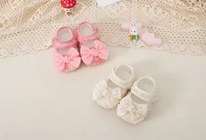 Detail of baby girl walking shoes featuring lace texture, large bows, and pearl accents