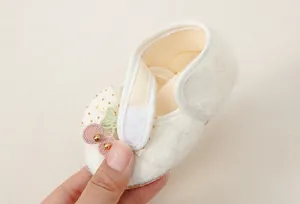 Dettaglio scarpe neonato in peluche con ricamo ciliegia e chiusura in velcro