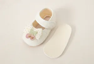 Dettaglio scarpe da principessa per neonata con fiocco in rete e ricamo a forma di ciliegia