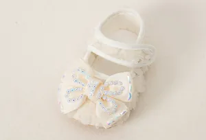 Detail of cream baby princess shoes with lace edges and rhinestone bow decoration