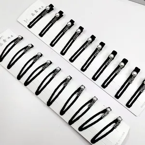 Détail de 10 pinces à cheveux en métal noir avec perles blanches et motifs logo cristal